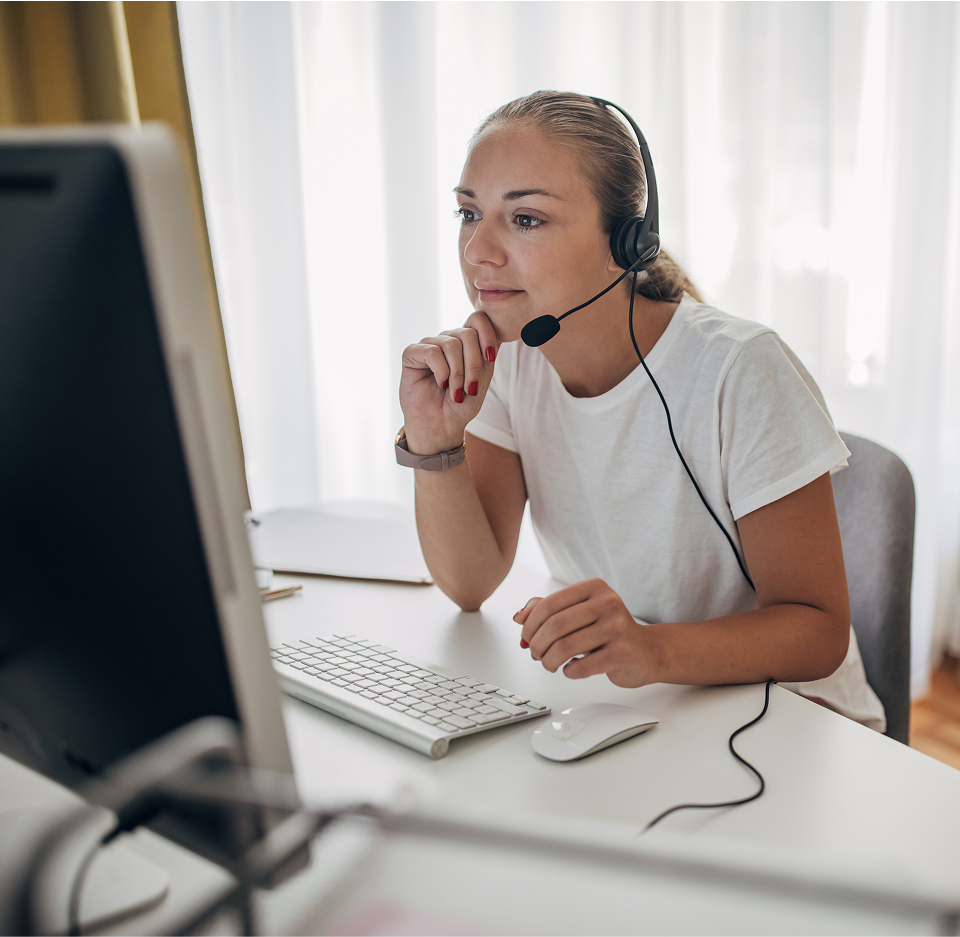 A person wearing a headset and looking at a computer screen
